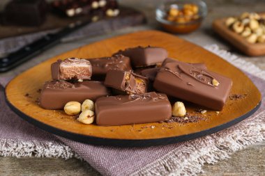 Delicious chocolate candy bars with nuts on wooden table, closeup