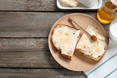 Slices of bread with butter, honey and milk on wooden table, flat lay. Space for text