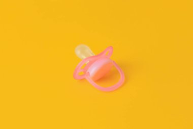 One new baby pacifier on orange background