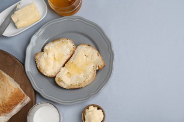 Sandwiches with butter, honey and milk on light grey table, flat lay. Space for text