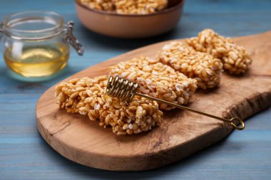 Board with puffed rice bars (kozinaki) on light blue wooden table, closeup