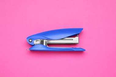New bright stapler on pink background, top view. School stationery