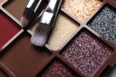 Beautiful eye shadow palette and brushes on table, closeup