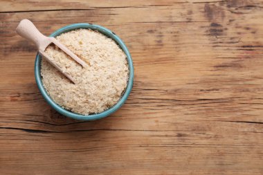 Scoop and bowl of brewer`s yeast flakes on wooden table, top view. Space for text