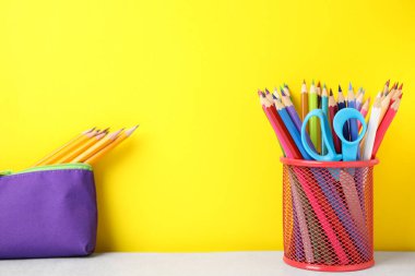 Different school stationery on white table against yellow background, space for text. Back to school