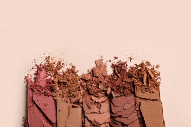 Different crushed eye shadows on beige background, flat lay. Space for text
