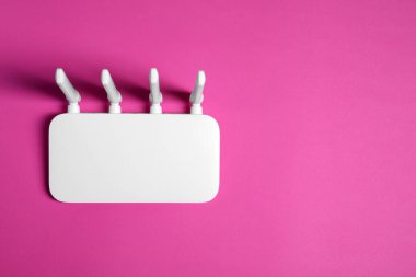 New white Wi-Fi router on pink background, top view. Space for text