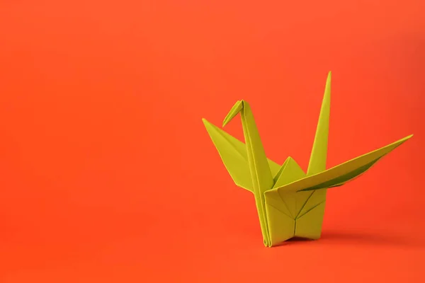 Origami art. Handmade paper crane on orange background, space for text