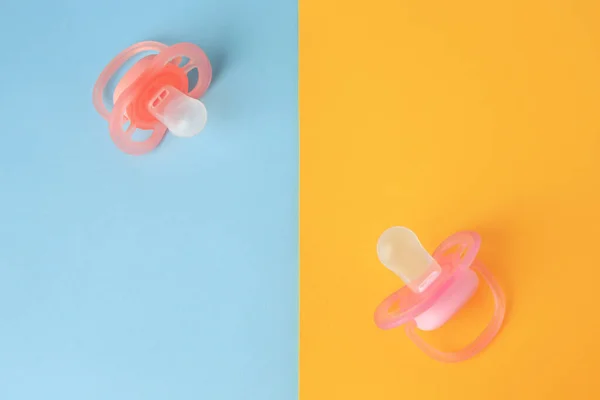 New baby pacifiers on color background, flat lay