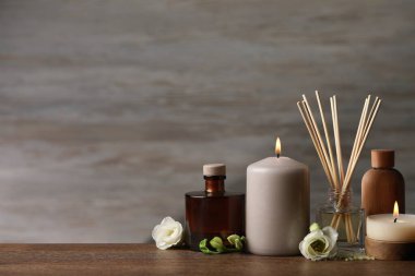 Beautiful composition with burning candles and different spa products on wooden table. Space for text