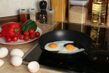 Cooking eggs for breakfast in frying pan on cooktop
