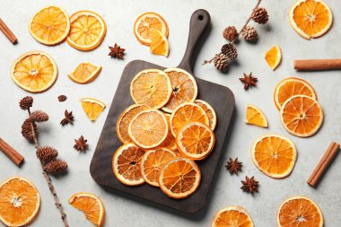 Dry orange slices, cinnamon sticks and anise stars on light grey table, flat lay