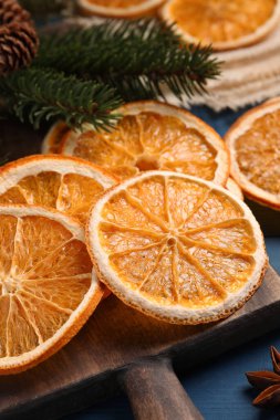 Dry orange slices and fir tree branches on wooden table, closeup