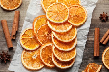 Many dry orange slices and spices on wooden table, flat lay