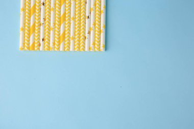Many paper drinking straws on light blue background, flat lay. Space for text