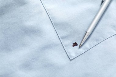 Pen and stain of black ink on light shirt, top view. Space for text