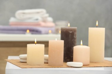 Beautiful spa composition with burning candles and stones on white table in wellness center