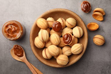 Delicious nut shaped cookies with boiled condensed milk on gray textured table, flat lay