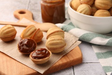 Delicious nut shaped cookies with boiled condensed milk on table, closeup
