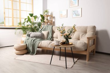 Stylish room interior with beautiful flowers and comfortable sofa