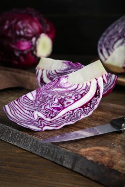 Pieces of fresh red cabbage and knife on wooden table