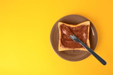 Tasty toast with chocolate paste and flax seeds on yellow background, top view. Space for text