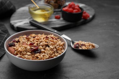 Tasty granola served with nuts and dry fruits on black table. Space for text