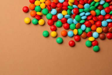 Tasty colorful candies on light brown background, above view. Space for text
