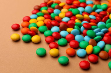 Tasty colorful candies on light brown background, closeup