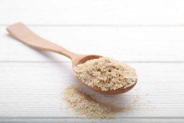 Beer yeast flakes and spoon on white wooden table, closeup