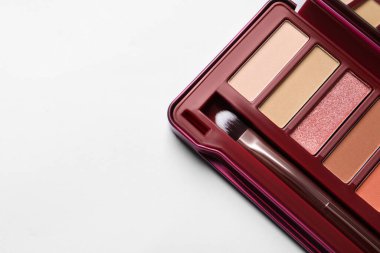 Beautiful eye shadow palette and brush on white table, top view. Space for text