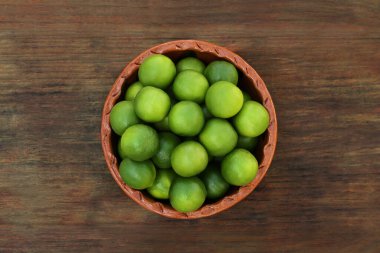 Fresh ripe limes in bowl on wooden table, top view