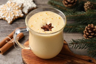Glass of delicious eggnog with anise star on wooden table