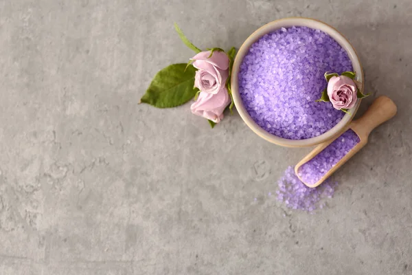 Purple sea salt and beautiful flowers on light grey table, flat lay. Space for text