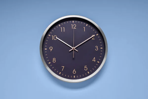 Stylish round clock on light blue background, top view. Interior element
