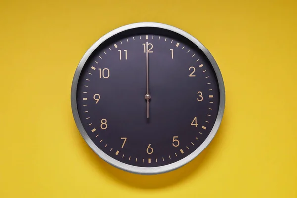 Stylish round clock on yellow background, top view. Interior element