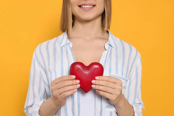 Young Woman Holding Red Heart Yellow Background Closeup Volunteer Concept — Stockfoto