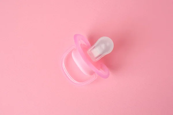 New baby pacifier on pink background, top view