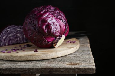 Taze kırmızı lahanayı ahşap masada koyu arka planda kestim.