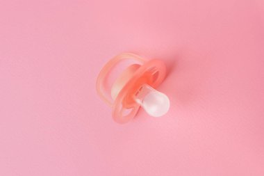 New baby pacifier on pink background, top view