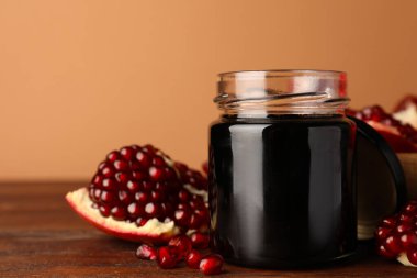 Cam kavanoz lezzetli nar sosu ve ahşap masada taze olgun meyve. Metin için boşluk