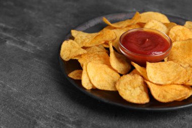 Gri masada ketçaplı lezzetli cipsler, yakın plan. Metin için boşluk