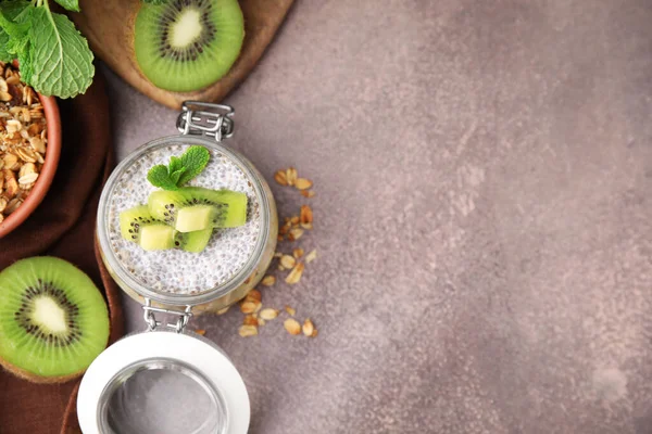 Delicious dessert with kiwi, fresh cut fruits and muesli on brown table, flat lay. Space for text