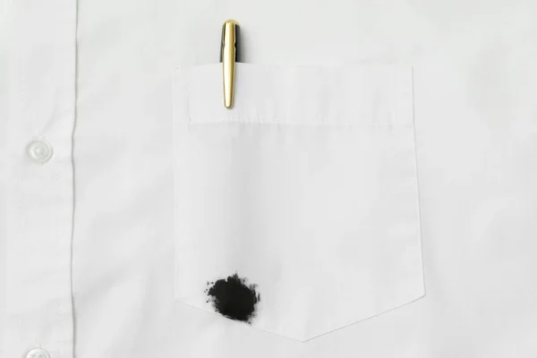 White shirt with stain of black ink and pen in pocket, top view