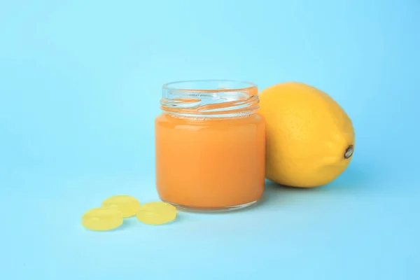 Cough drops, fresh lemon and honey on light blue background