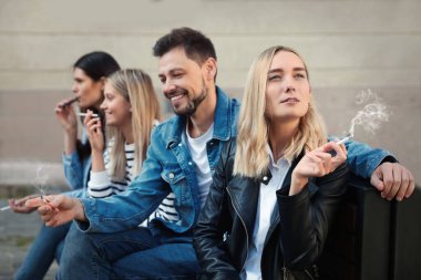 İnsanlar açık havada sigara içiyor.