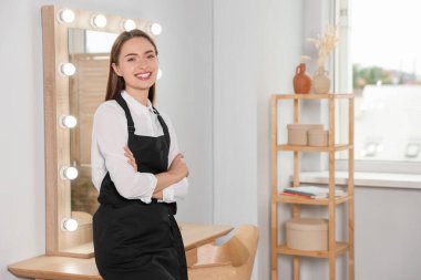 Portrait of professional hairdresser wearing black apron in beauty salon