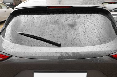 Araba sileceği temizleme suyu arka camın camından düşer, yakın plan.