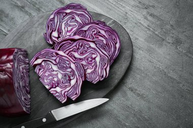Slices of fresh ripe red cabbage and knife on grey table, flat lay. Space for text