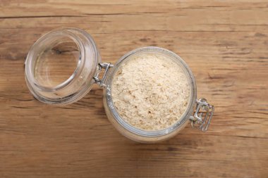 Ahşap masada bira mayası taneli cam kavanoz, üst manzara.